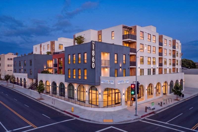 The 1860 at dusk — apartments above arched ground-floor retail on a Los Feliz corner